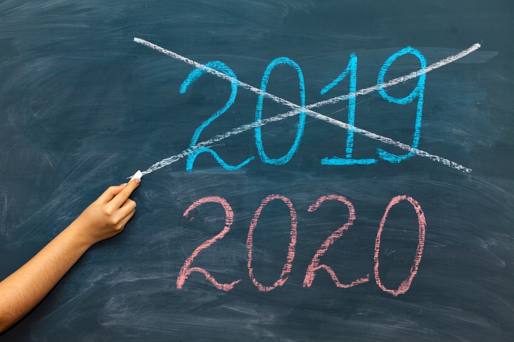 happy new year 2020. Chalkboard with 2020, crossed 2019 and hand with chalk